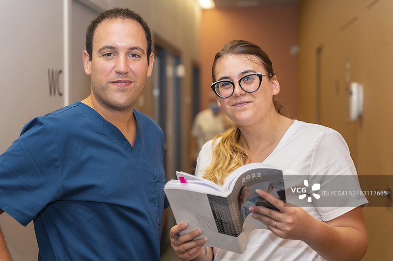 牙科诊所，助手与牙医在诊室走廊查看客户日程的肖像图片素材