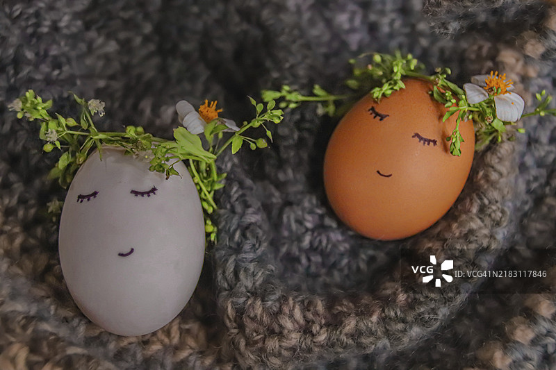 两个装饰有花朵的彩绘面孔复活节彩蛋放在羊毛上图片素材