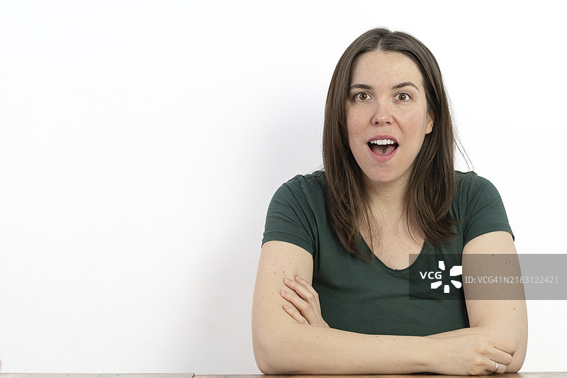 长发棕发女性惊讶地张嘴看向镜头，背景为白色图片素材