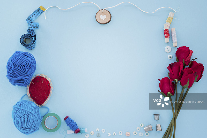 蓝色毛线测量带、线轴、纽扣、顶针、玫瑰，蓝色背景图片素材