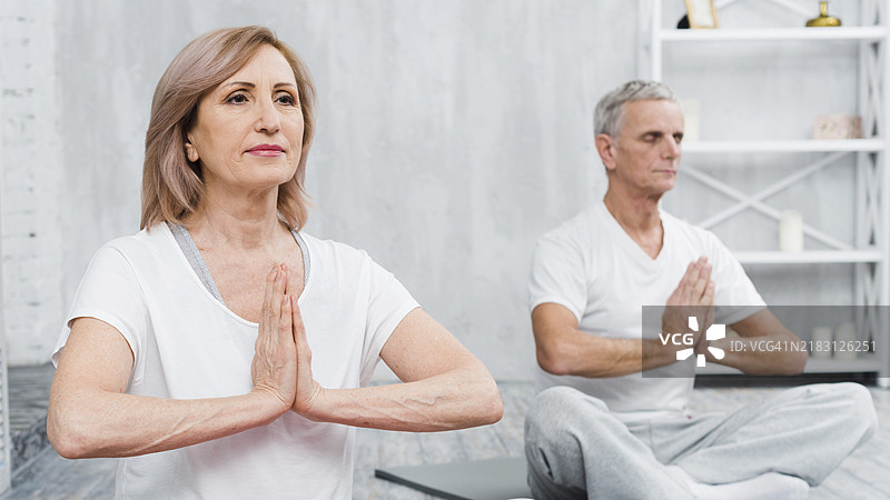 健康的老年夫妇坐在莲花坐姿，双手合十祈祷图片素材
