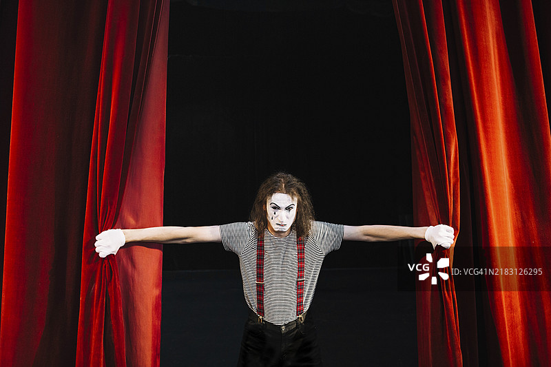 愤怒的男性哑剧演员握着红色帷幕图片素材