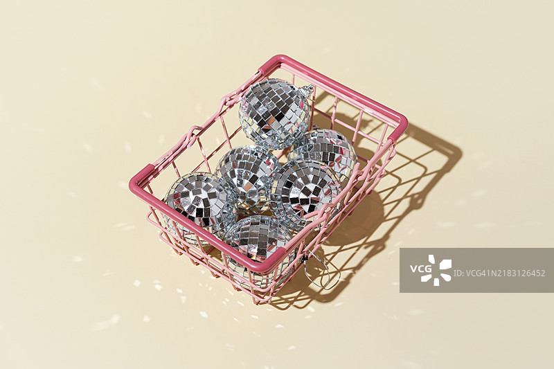 带有圣诞装饰球的购物篮，背景为米色。圣诞购物和促销活动。俯视图，留白空间。图片素材