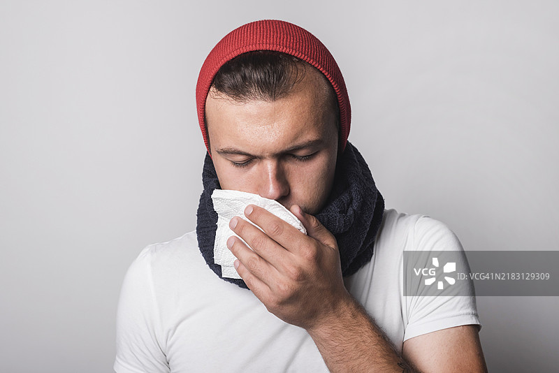 年轻男子在灰色背景下感冒发烧图片素材