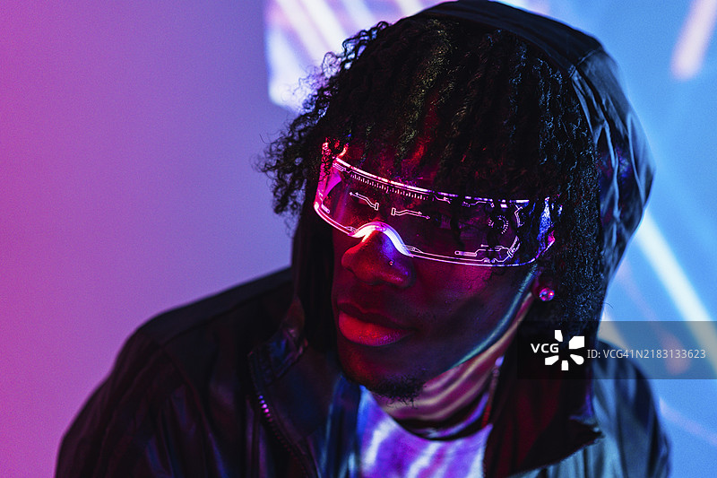 带有紫色和蓝色霓虹灯的工作室肖像，展示了一位酷炫的未来主义男子，佩戴增强现实眼镜。图片素材