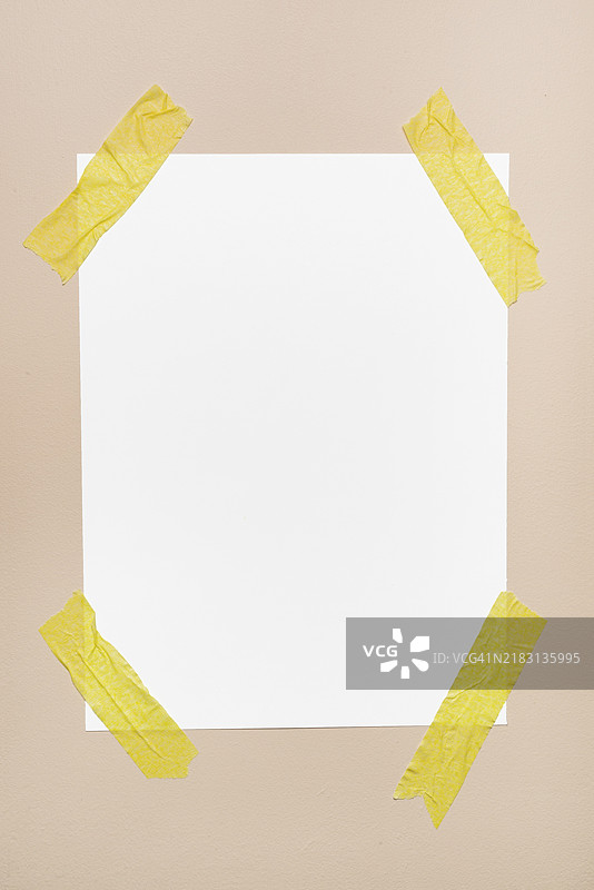 白色纸张贴在墙上，旁边有黄色胶带图片素材