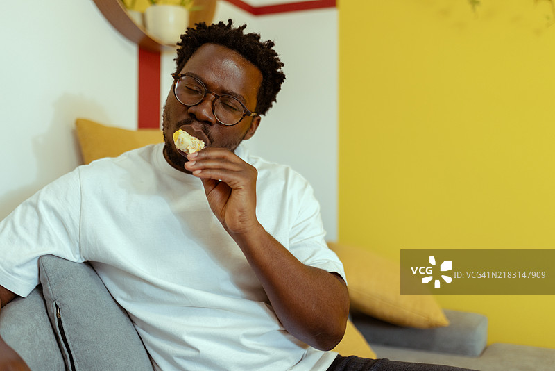 这位黑人小心翼翼地吃着冰淇淋棒，因为他的牙齿非常敏感，对寒冷有反应。图片素材