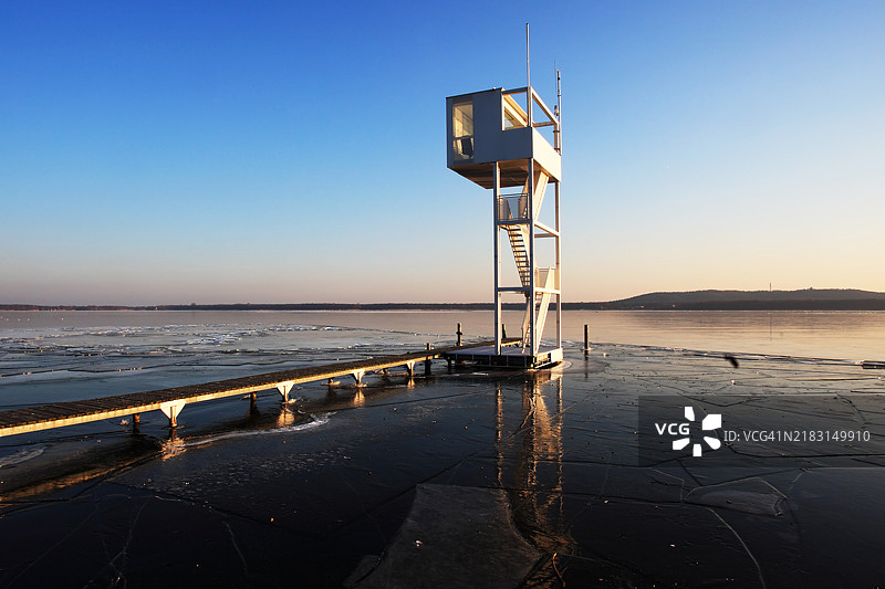 日落时分，冰冻湖面上有救生员塔图片素材