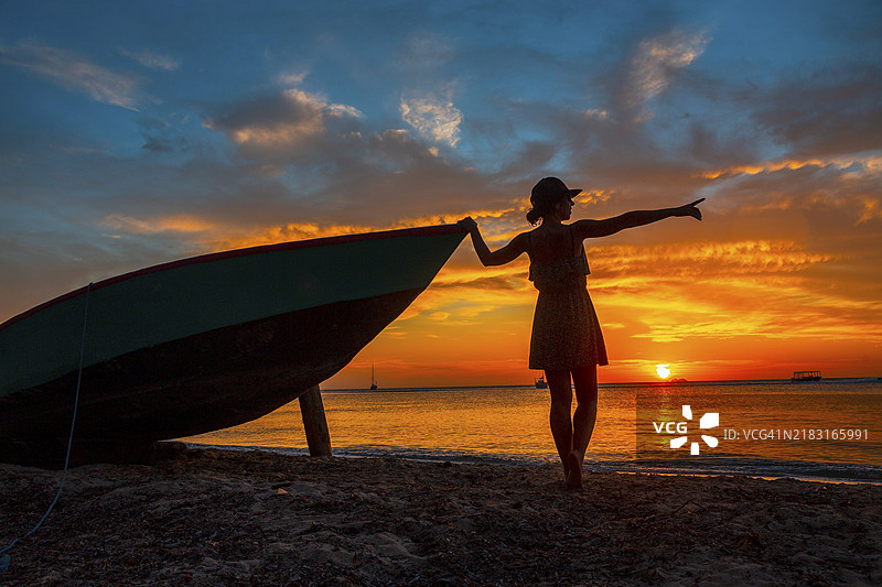 一位年轻女性在洪都拉斯西端的罗阿坦日落时分的船上。图片素材