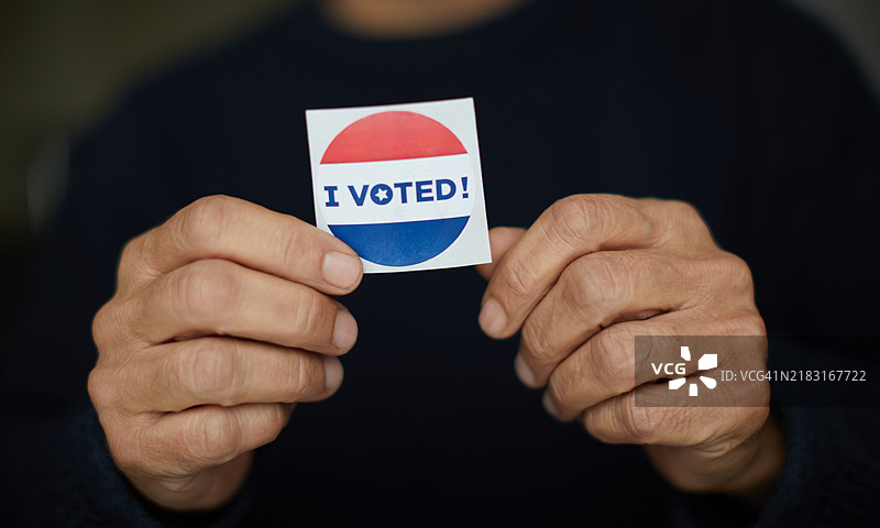 特写镜头：一位老年人手握“我投票”贴纸图片素材