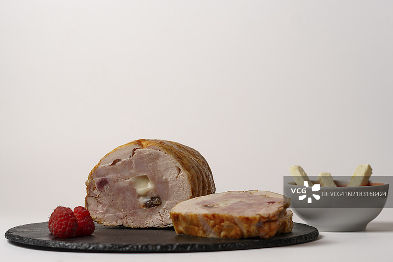 鸡肉填充了覆盆子和山羊奶酪，旁边有一碗覆盆子酱，背景为白色。图片素材