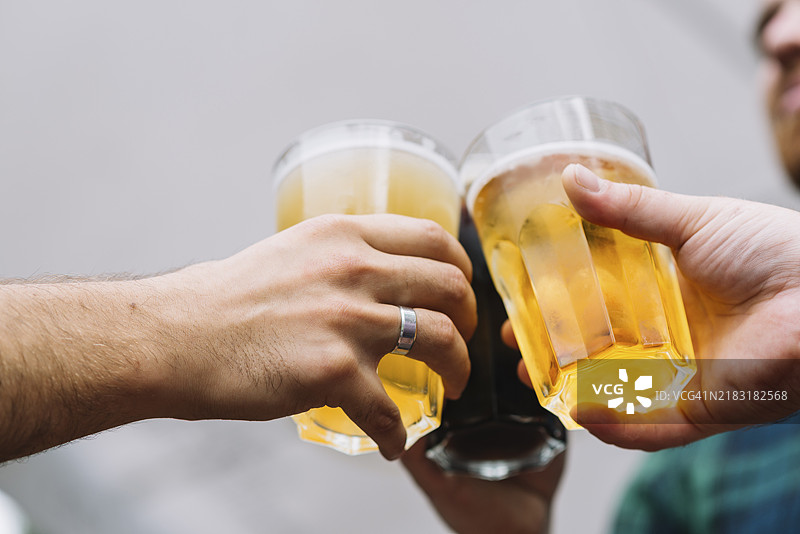 朋友的手举着啤酒杯祝酒图片素材