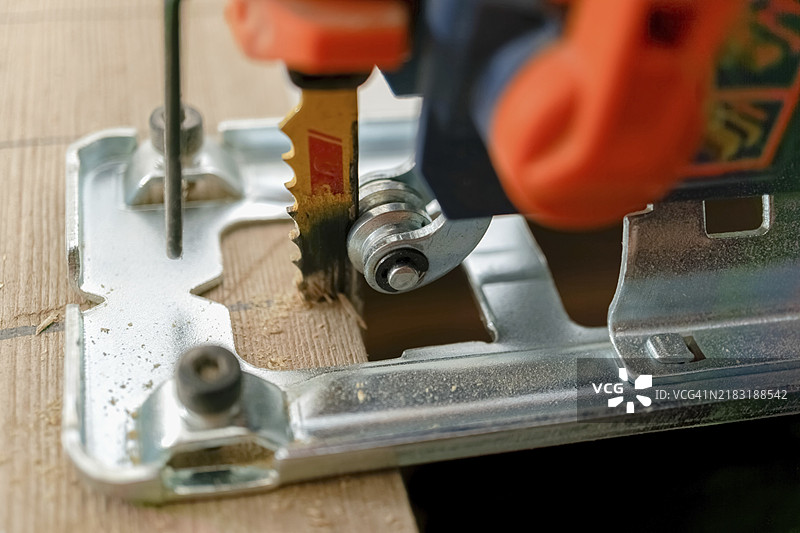 电锯特写，锯片正在切割木屑，木屑从木材中飞溅而出。图片素材