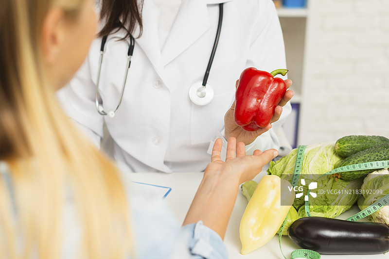 医生与病人近距离接触，手中拿着蔬菜图片素材
