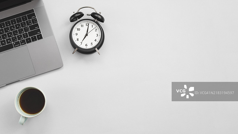 办公桌上的笔记本电脑和时钟图片素材