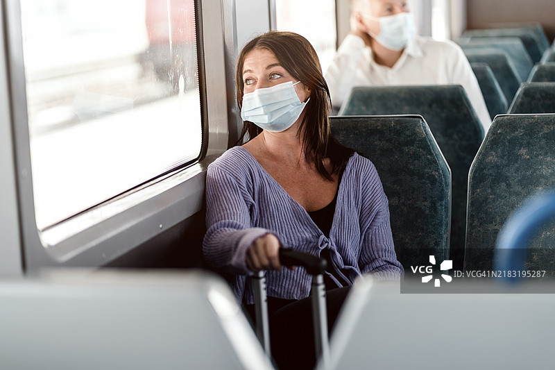 在火车日游中佩戴防护口罩的严肃乘客图片素材