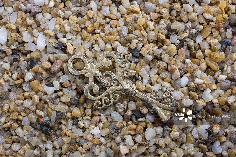 复古风格的装饰钥匙放置在沙质纹理上图片素材