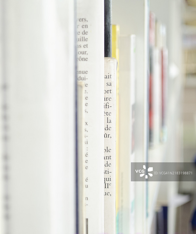 模糊背景的旧书。明亮房间中的白色纸质书籍放在白色书架上。图片素材