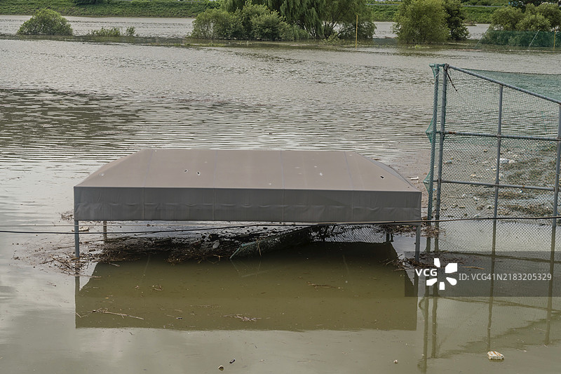 大田市河滨公园棒球场的长椅顶部被洪水淹没，经过倾盆大雨的季风。图片素材