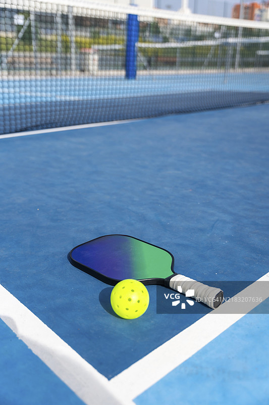 垂直照片，场地上有球拍和黄色的皮克球，留有空白区域。图片素材