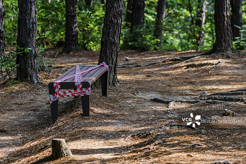 公园长椅上贴有“危险，请勿使用”的胶带，以防止COVID-19传播图片素材