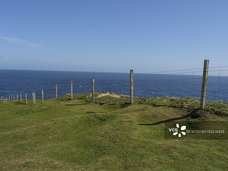 沿海的草地景观，篱笆环绕，视野延伸至蓝色海洋的地平线，勒威克，设得兰群岛，苏格兰，英国图片素材