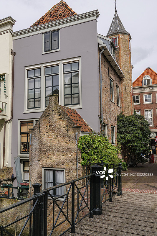 荷兰多德雷赫特一条安静街道上，桥边的房屋拥有砖砌外立面、大窗户和绿色植物。图片素材