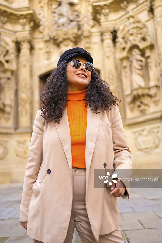 时尚的拉丁女性穿着温暖优雅的衣服，站在一个有古老纪念碑的广场上图片素材