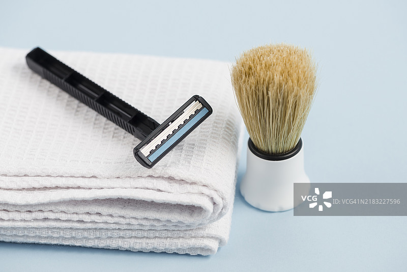 白色折叠餐巾与经典剃须刷在蓝色背景下图片素材
