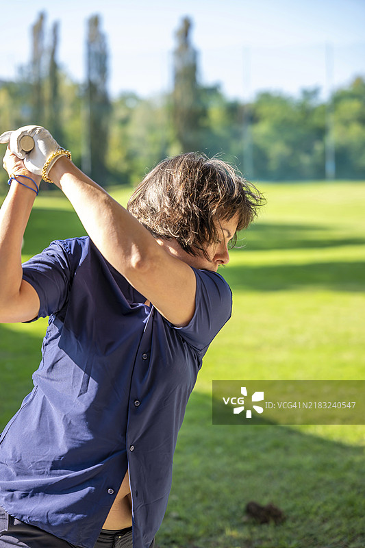 瑞士阳光明媚的日子里，一位女性高尔夫球手正在挥杆。图片素材