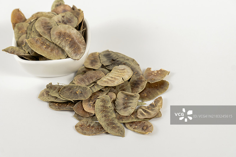 亚历山大决明荚。含有排毒和净化特性的决明子，放在一个白色陶瓷碗中，背景为白色。图片素材