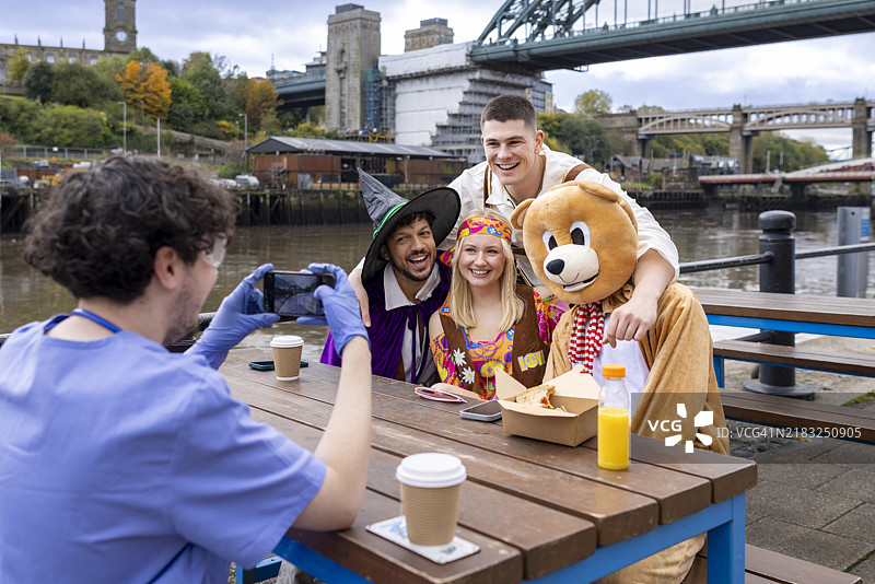 穿着华丽服装的好友们在用手机拍照图片素材