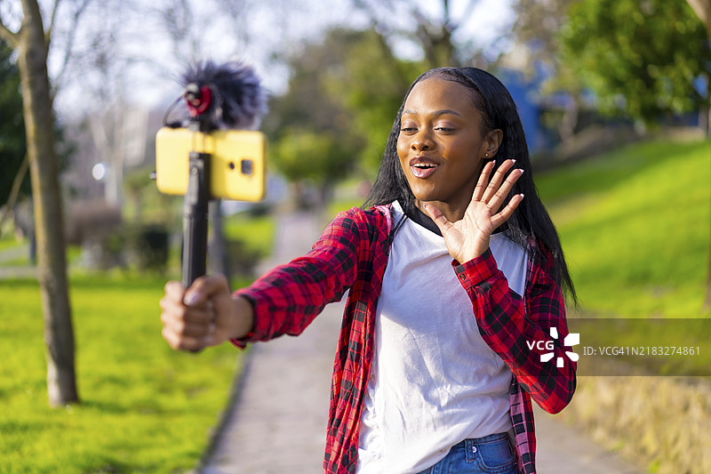 在城市公园中，主播用手机进行在线视频时做手势图片素材