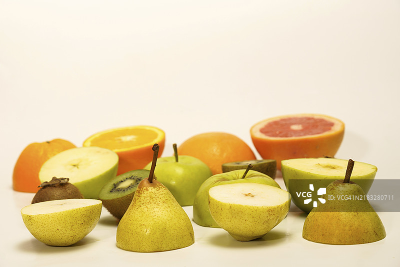 新鲜水果切成两半，孤立在白色背景上。梨、猕猴桃、苹果、橙子、葡萄柚图片素材