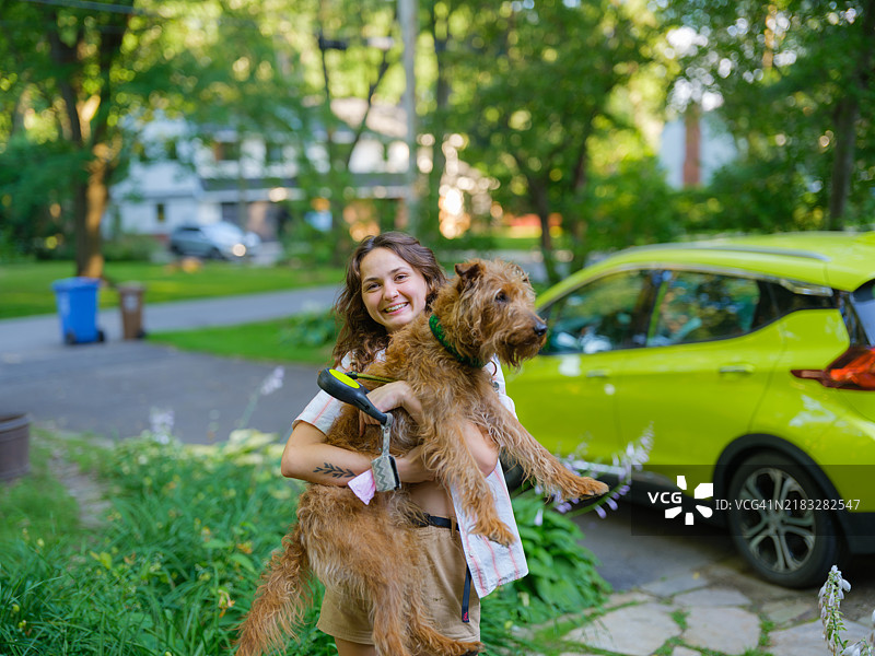 夏季郊区，快乐的女人抱着狗狗。图片素材