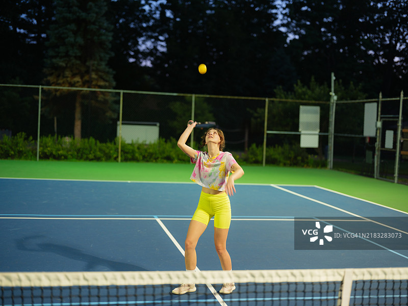 黄昏时分，女性在打单打皮克球图片素材