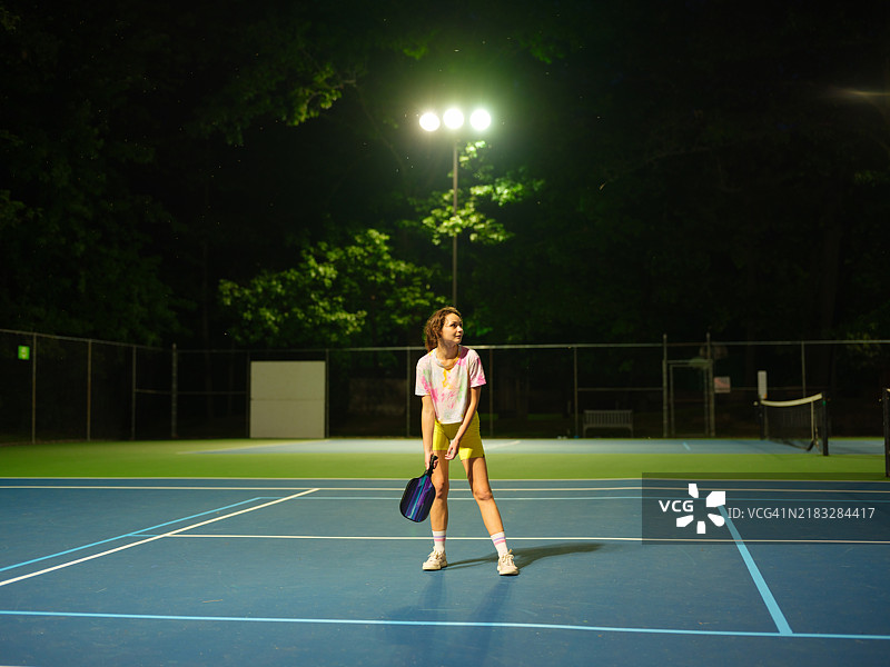 黄昏时分，女子在打单打皮克球图片素材