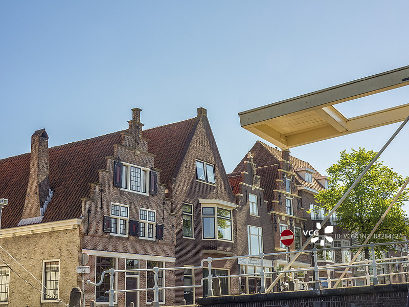 阿尔克马尔，荷兰，运河旁的历史砖砌建筑排成一行，桥下方在晴朗的天空下。图片素材