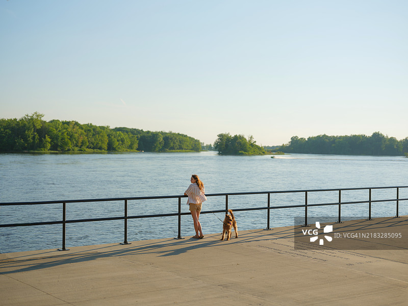 在加拿大魁北克的运河旁散步的女人和狗图片素材