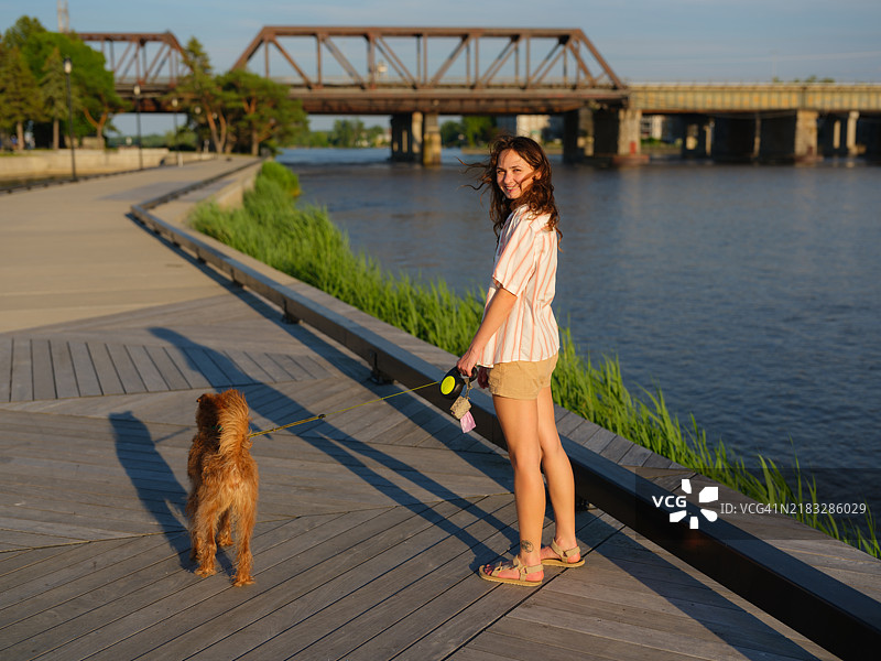 在加拿大魁北克的运河旁散步的女人和狗图片素材