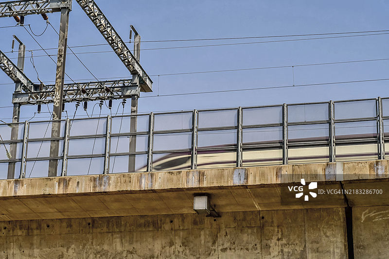 低角度视图的高速列车穿越位于韩国的混凝土铁路桥，桥下是电力变压器站。图片素材