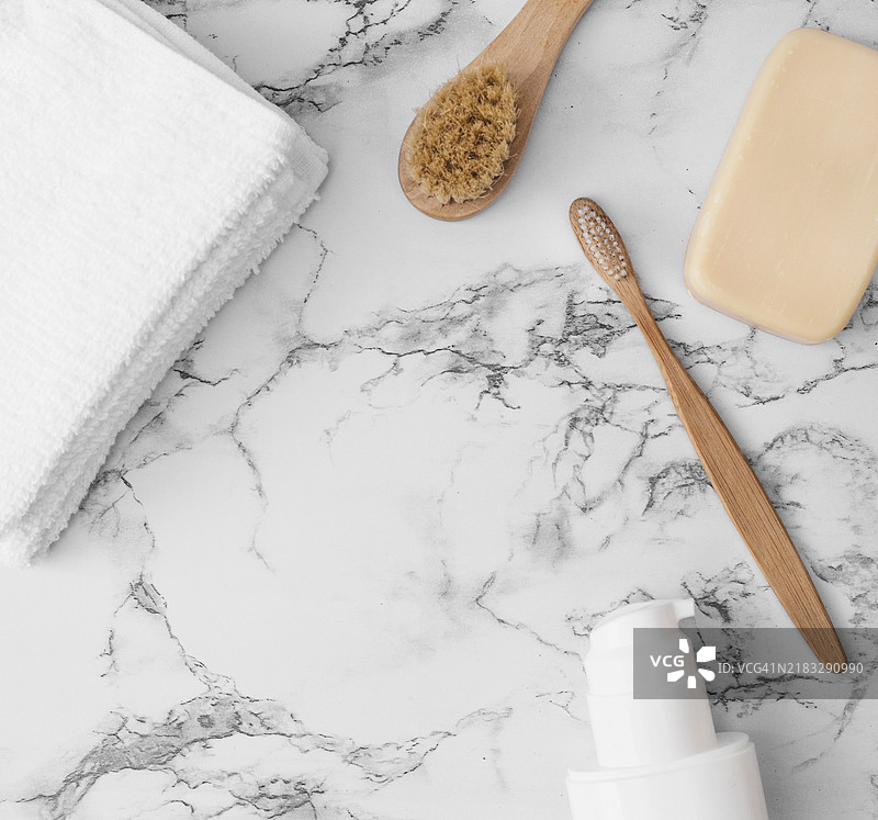 高角度视图的毛巾、刷子、肥皂和化妆品瓶，放置在大理石表面上图片素材