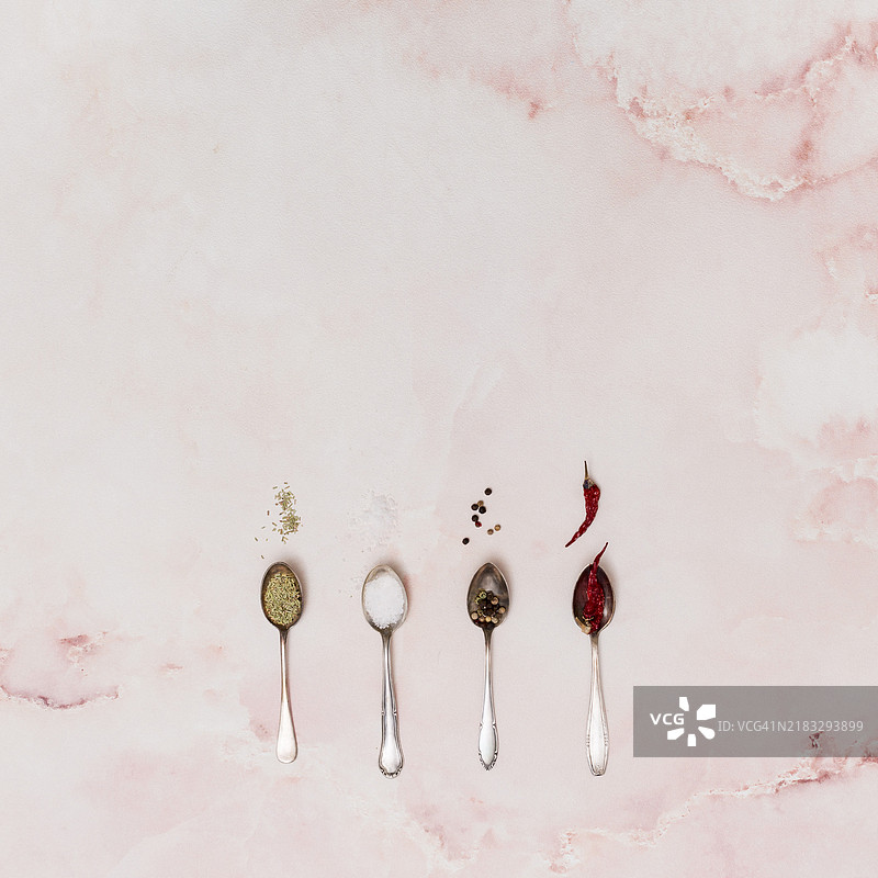 装满香料的勺子排列在旧粉色背景上图片素材