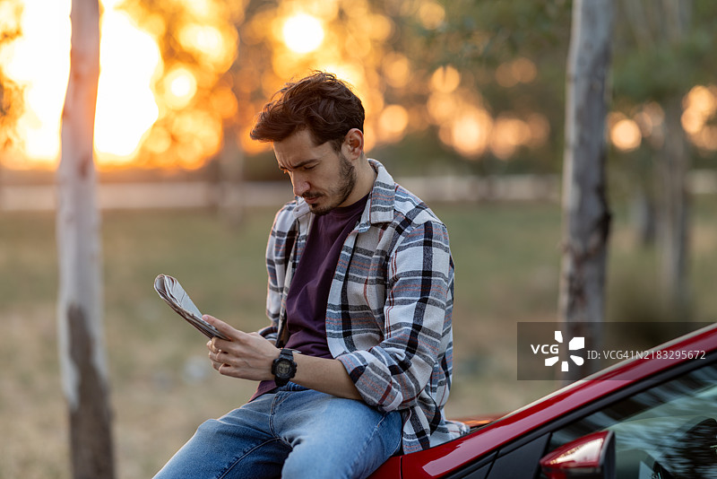 年轻男子在旅行前阅读当地报纸的日程安排和最新新闻。图片素材
