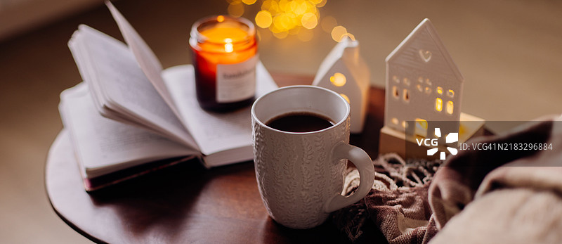 圣诞静物。白色杯子里的热巧克力，翻开的书，燃烧的蜡烛和圣诞装饰。圣诞快乐。冬季舒适的生活方式。图片素材
