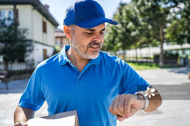 快递员在送包裹时查看时间图片素材