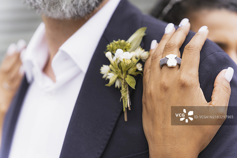 多元文化的情侣在美丽的婚礼上拥抱，手中捧着戒指，庆祝婚礼仪式。图片素材