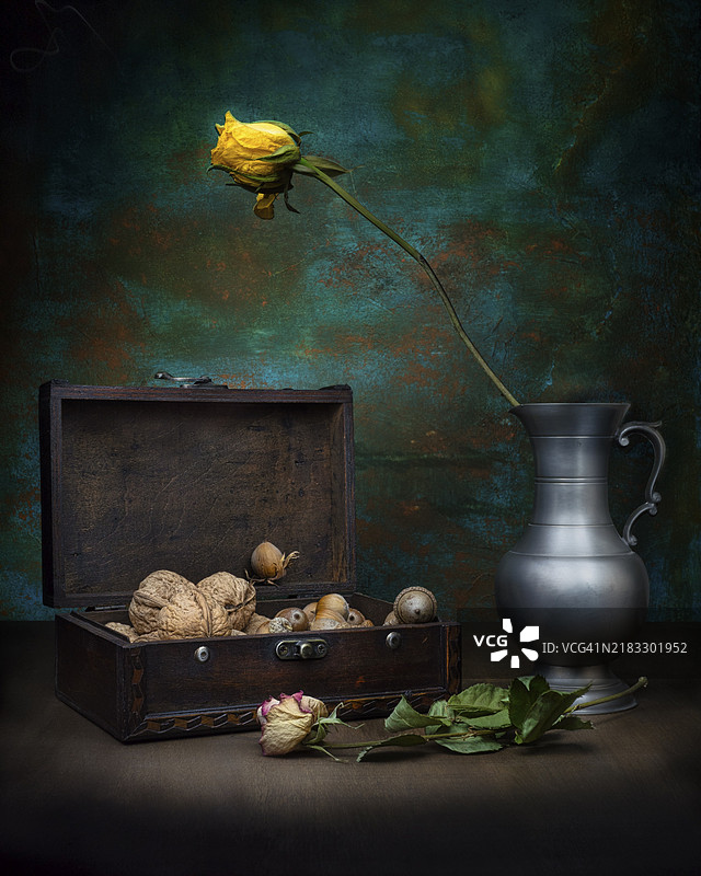 生命与死亡的主题，陈列着坚果的旧木箱旁放着枯萎的玫瑰花银壶，摄影棚拍摄，象征性照片图片素材