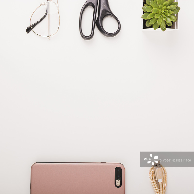 高角度视图的智能手机、USB线、盆栽植物、剪刀、眼镜，白色背景图片素材