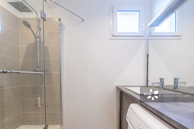 明亮的新浴室室内，配有瓷砖玻璃淋浴和梳妆柜，室内设计简约。图片素材